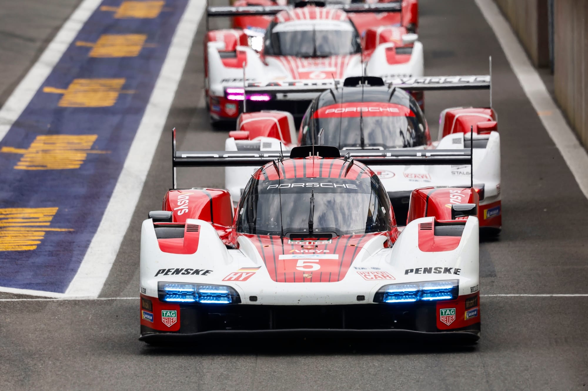 The #5 Porsche, #99 Proton Porsche, and #6 Porsche exiting the pitlane at Spa.