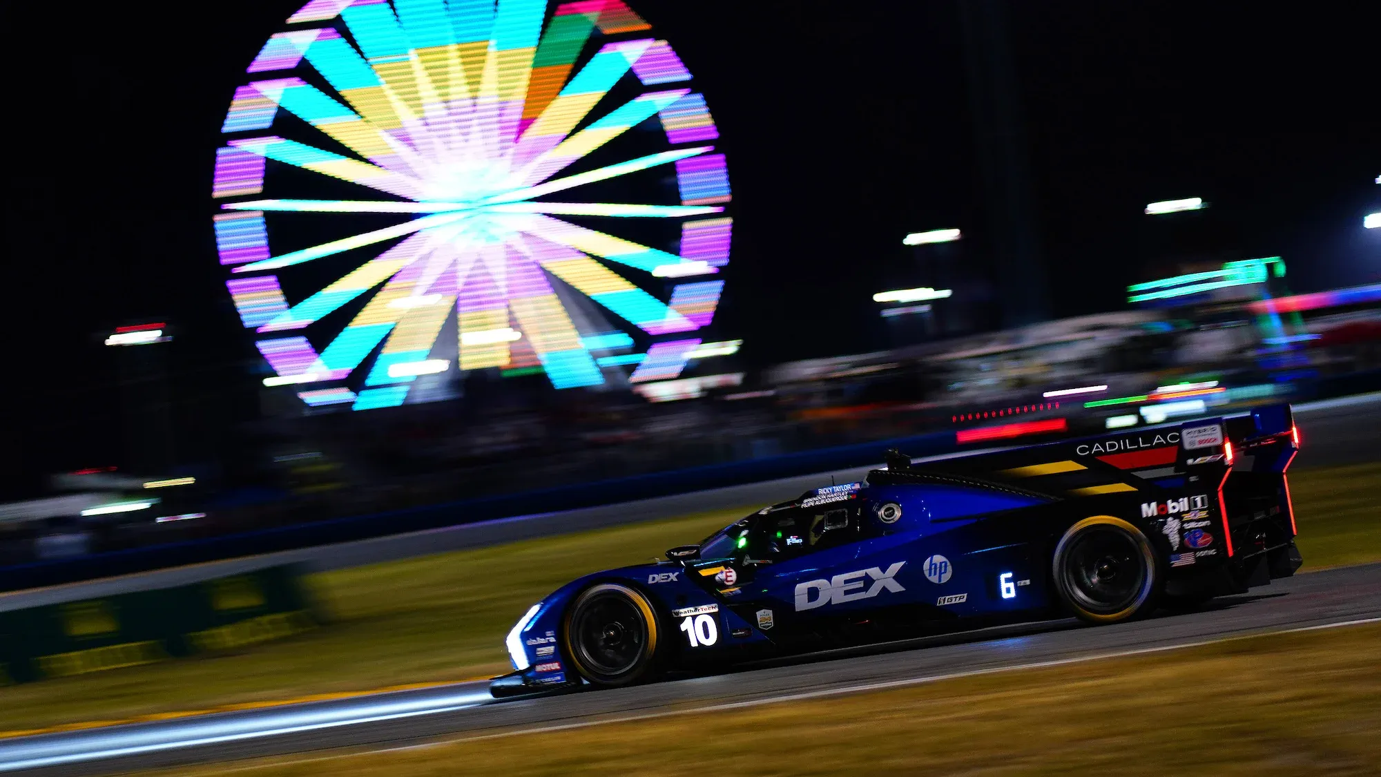 The #10 Wayne Taylor Racing Cadillac illuminated in darkness at Daytona, with the illuminated big wheel in the background.