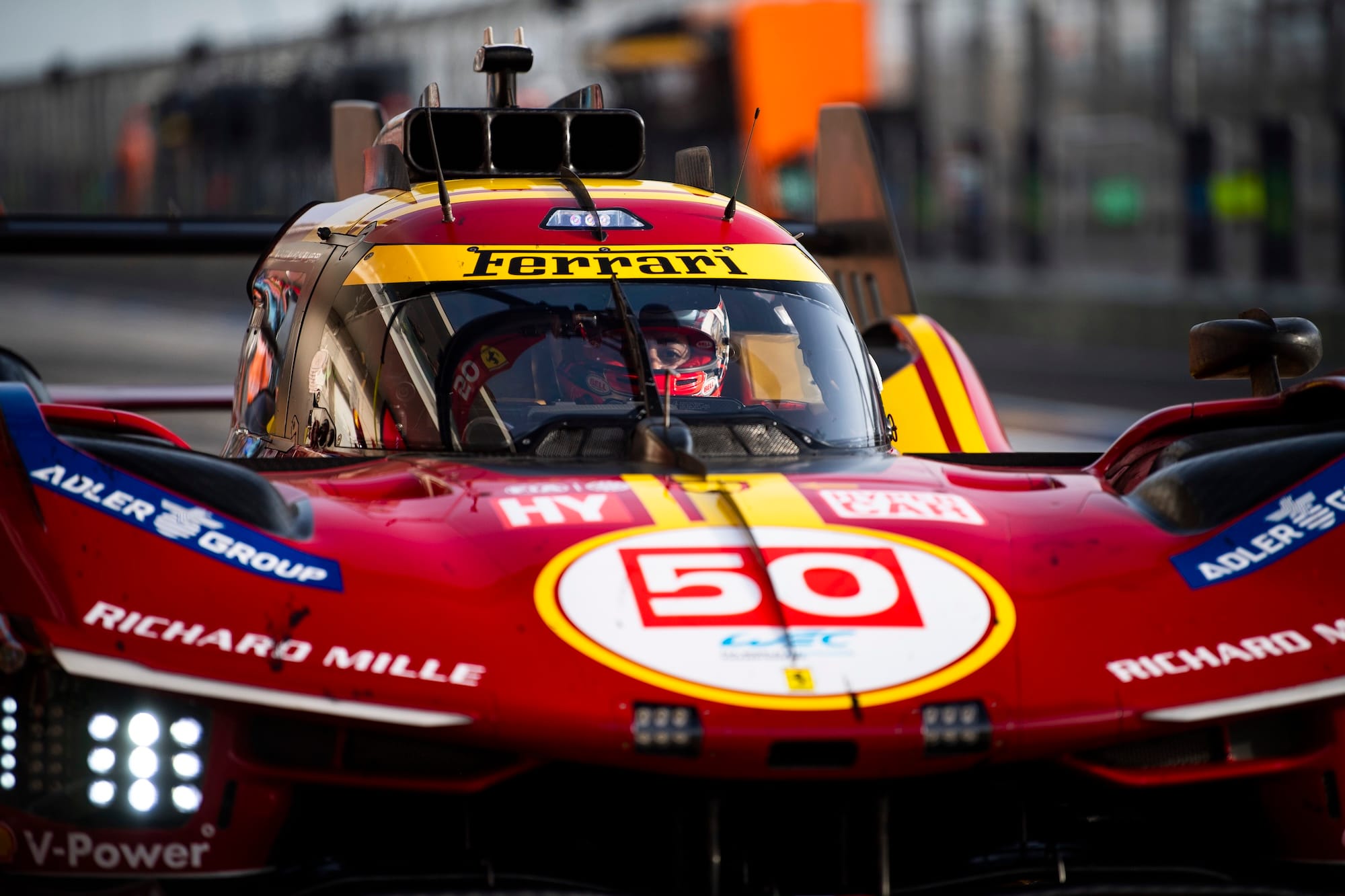 The #50 Ferrari 499P in the pitlane at Qatar's Lusail International Circuit, with the driver's eyes visible through the windscreen.