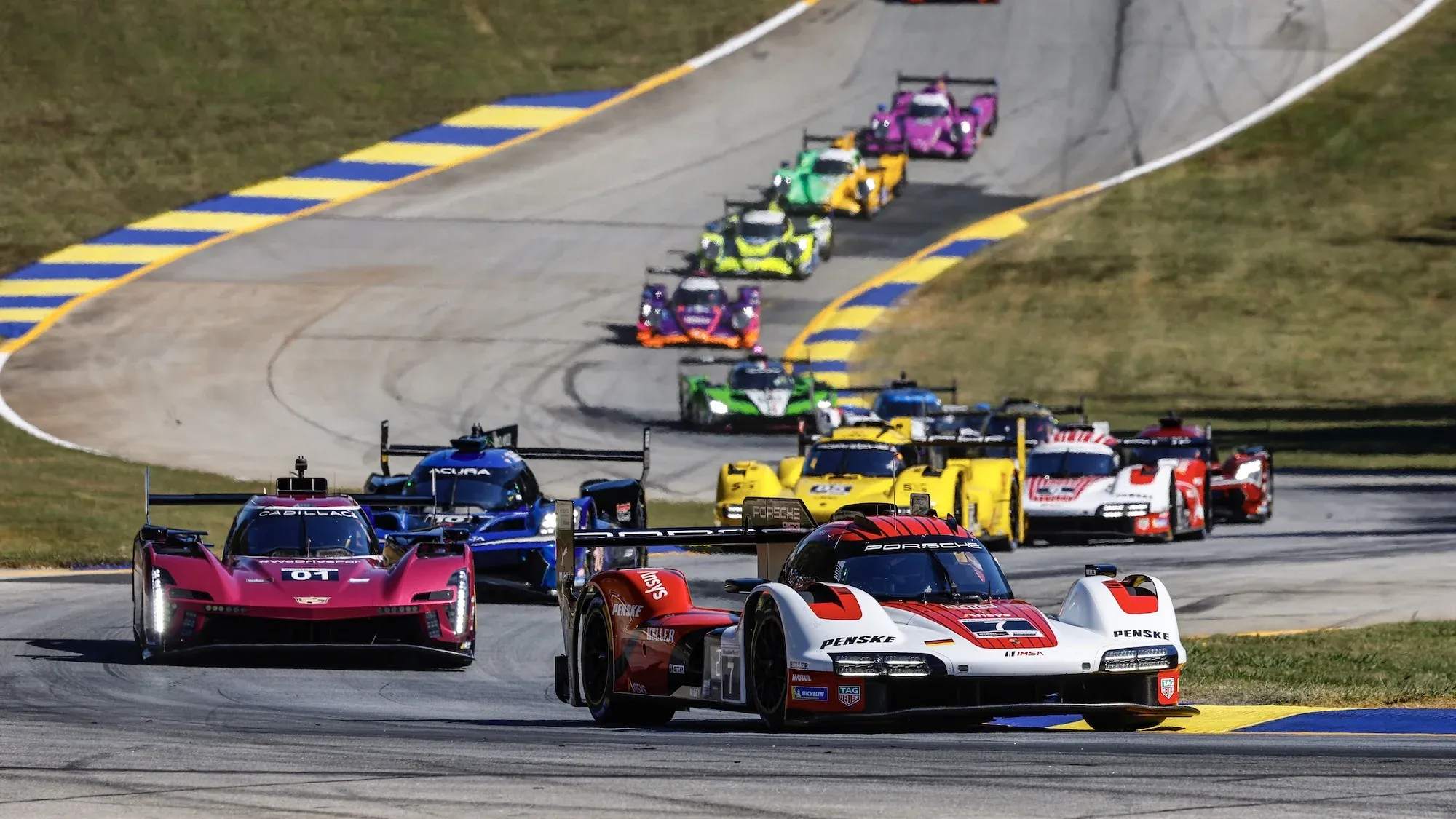 The #7 Porsche 963 leading a train of cars exiting the esses at Road Atlanta, 2024.